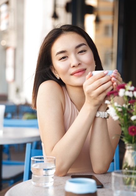 Portret van gelukkige jonge zakenvrouw met mok in handen koffie drinken in de ochtend in restaurant