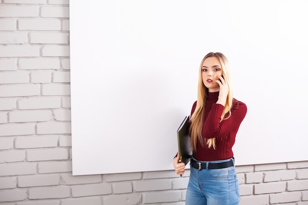 Portret van gelukkige jonge zakenvrouw vrouw in de buurt van op witte muur.