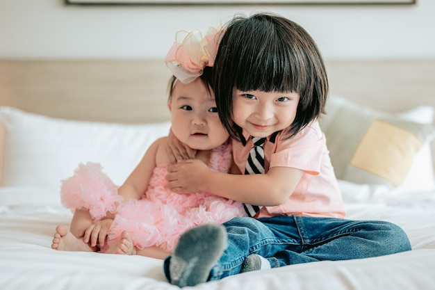 Portret van gelukkige kinderen spelen in witte slaapkamer Kleine jongen en meisje broer knuffelen zusje op het bed Gelukkige familie lifestyle concept