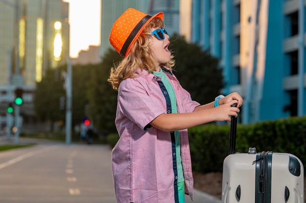 Portret van gelukkige kindreiziger met bagage Positieve kleine toerist met koffer klaar om te reizen Gelukkige kindtoerist met bagage die op vakantie gaat reizen