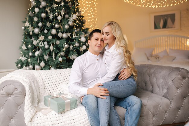 Portret van gelukkige man met zijn mooie vrouw knuffels thuis tijdens de kerstvakantie.