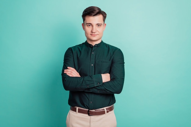 Portret van gelukkige marketeer man die handen kruist geïsoleerd over groenblauw achtergrond