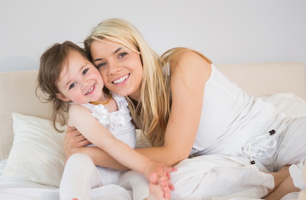 Portret van gelukkige moeder en dochter zittend op bed