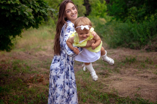 Portret van gelukkige moeder speelt met haar kleine babymeisje en glimlacht in het park