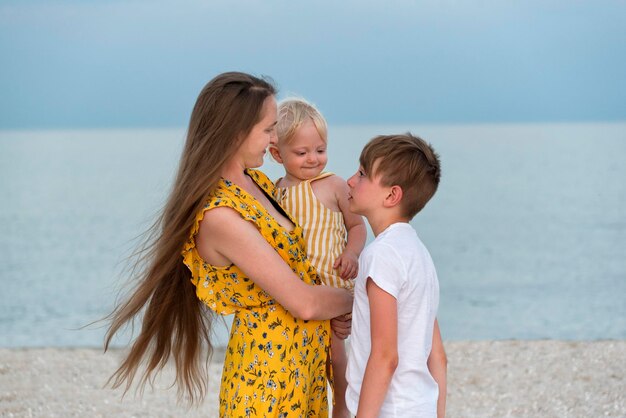 Portret van gelukkige mooie moeder met dochtertje en oudste zoon op zee achtergrond Familie vakantie