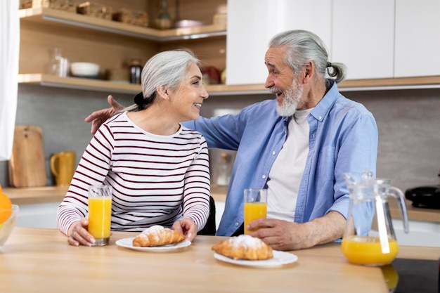 Portret van gelukkige oudere echtgenoten die samen snacks in de keuken hebben