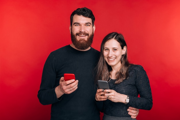 Portret van gelukkige paarholding smartphones en het bekijken de camera