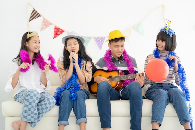 Portret van gelukkige tienerjaren die de gitaar spelen omringd door vrienden