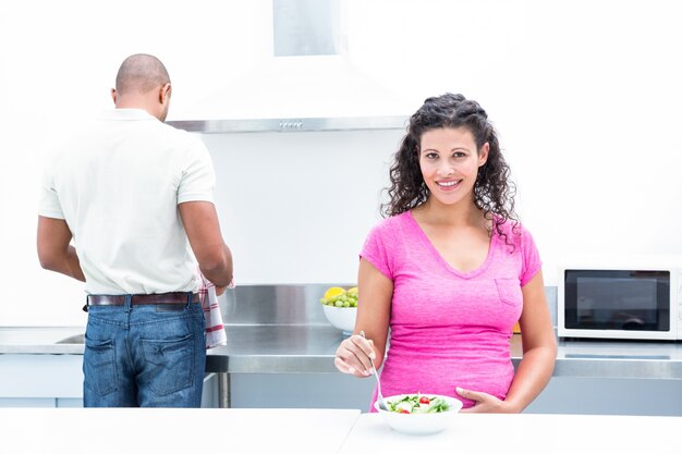 Portret van gelukkige vrouw met echtgenoot die in keuken helpen