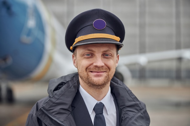 Portret van gelukkige zelfverzekerde blanke vliegtuigbemanning in de buurt van vliegtuig