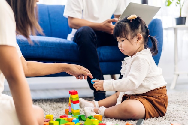 Portret van genieten van gelukkige liefde aziatische familie vader en moeder met een klein aziatisch meisje glimlachende activiteit leren en vaardigheid hersentraining spelen met speelgoed bouwen houten blokken bordspel thuis
