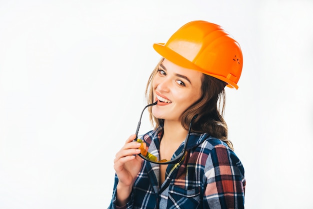 Portret van gepassioneerde vrouwelijke bouwer met helm en bril aan te raken haar lippen