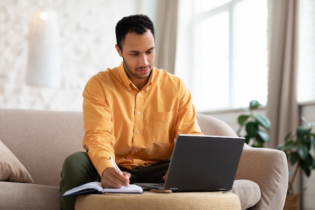 Portret van gerichte Arabische man die laptop gebruikt en schrijft