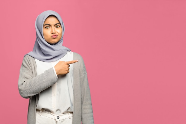 Foto portret van geschokte jonge aziatische vrouw die met vinger richt om ruimte te kopiëren