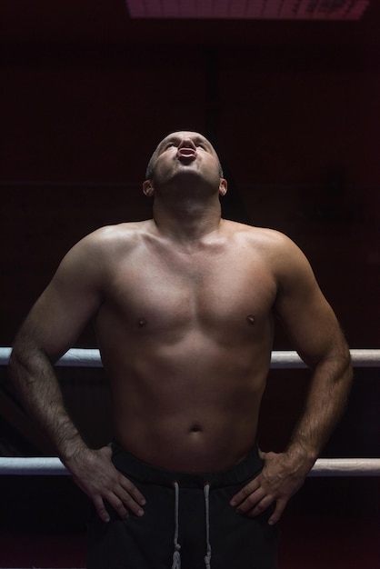 portret van gespierde professionele kickbokser die in de ring staat terwijl hij traint voor het gevecht