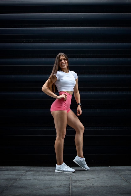 Portret van gespierde sexy Sportvrouw atleet met lang haar en sterke benen poseren in sportschool tegen zwarte achtergrond.