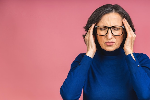 Portret van gestresste vermoeide zieke volwassen senior oude vrouw geïsoleerd over roze achtergrond.