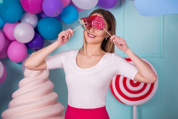 Portret van geweldige zoetekauwvrouw in roze jurk met snoepjes en poseren op achtergrond