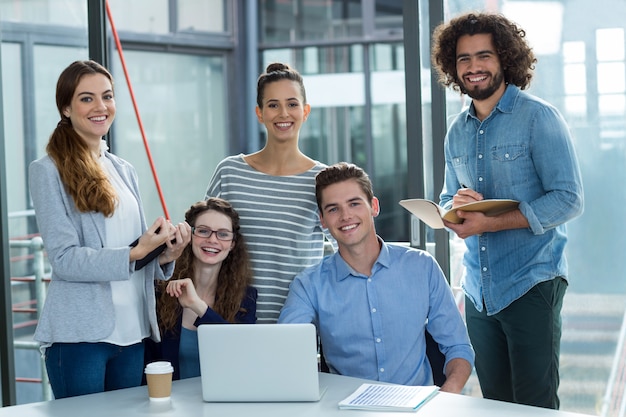 Portret van glimlachend commercieel team dat over laptop in vergadering bespreekt