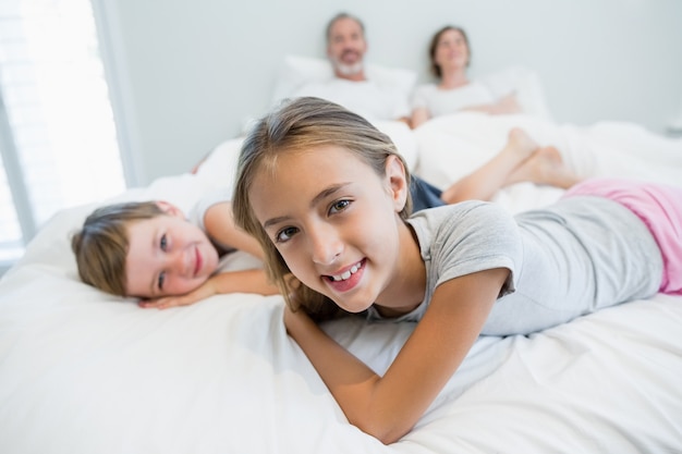 Portret van glimlachend meisje en jongen die op bed in slaapkamer liggen