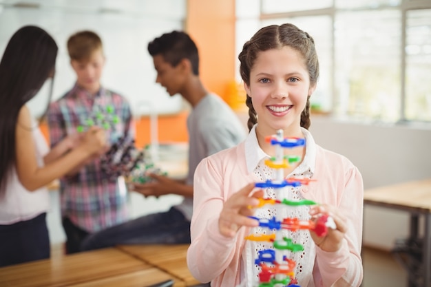 Portret van glimlachend schoolmeisje die het moleculemodel in laboratorium onderzoeken