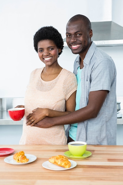 Portret van glimlachend zwanger paar die ontbijt in keuken hebben thuis