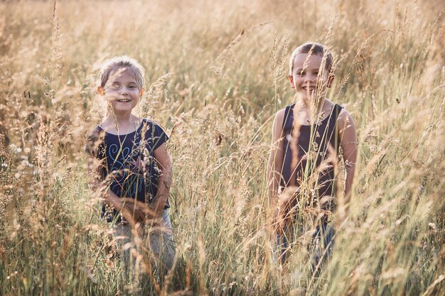 Foto portret van glimlachende broers en zussen die te midden van planten op het veld staan