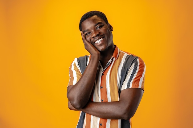 Portret van glimlachende jonge Afrikaanse man in gestreepte hemd tegen een oranje achtergrond