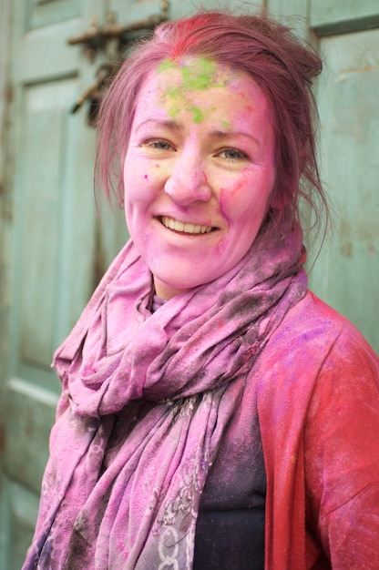 Portret van glimlachende jonge vrouw bedekt met poederverf tijdens Holi