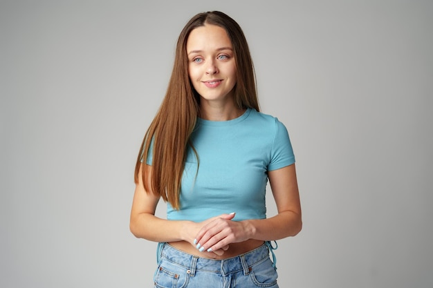 Portret van glimlachende jonge vrouw in blauw T-shirt op grijze achtergrond