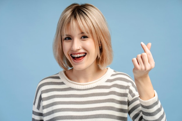 Portret van glimlachende jonge vrouw met beugels die het hart van de vingers toont k popcultuur