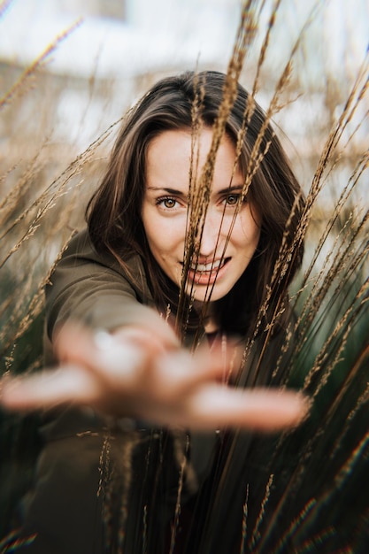 Portret van glimlachende jonge vrouw met gebaren te midden van planten