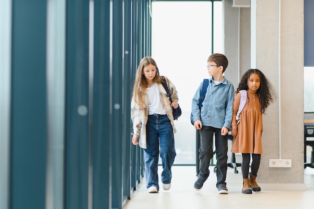 Portret van glimlachende kleine schoolkinderen in de schoolcorridor