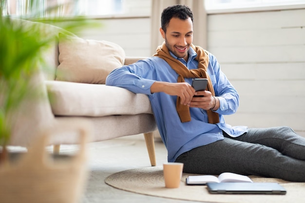 Portret van glimlachende man die smartphone thuis gebruikt