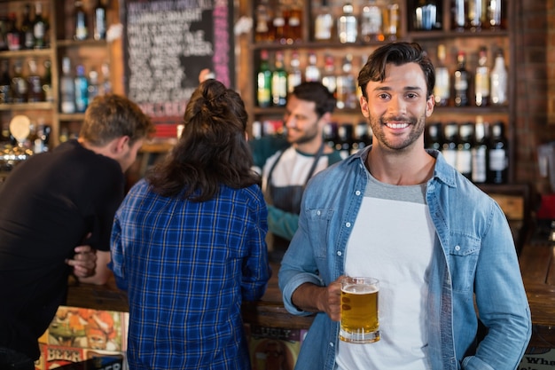 Portret van glimlachende man met bierpul ik bar