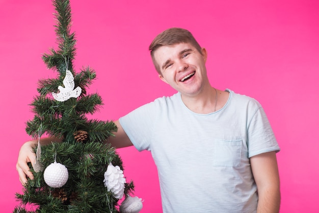 Portret van glimlachende man met kerstboom op roze