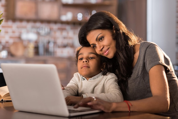 Portret van glimlachende moeder en dochter die laptop thuis gebruiken