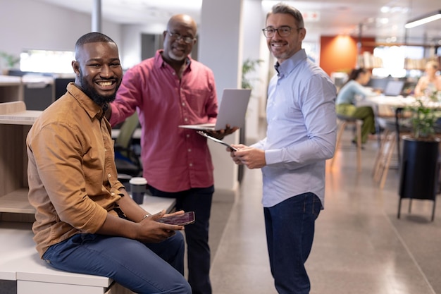 Portret van glimlachende multiraciale mannelijke zakencollega's met draadloze technologieën op modern kantoor