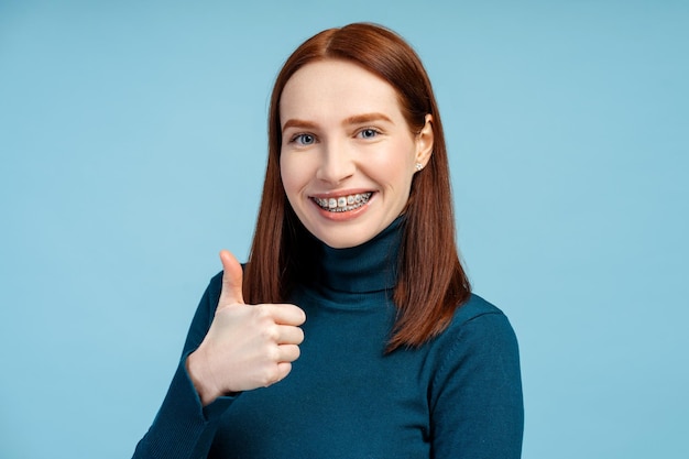 Portret van glimlachende roodharige vrouw hipster die naar de camera kijkt met een koel gebaar