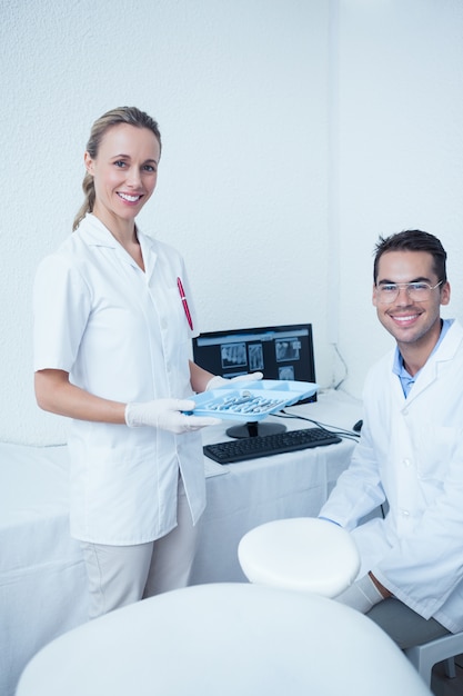 Portret van glimlachende tandartsen met computermonitor