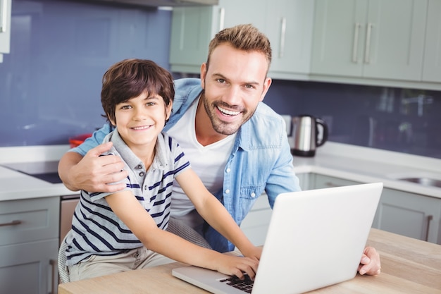 Portret van glimlachende vader en zoon die laptop met behulp van