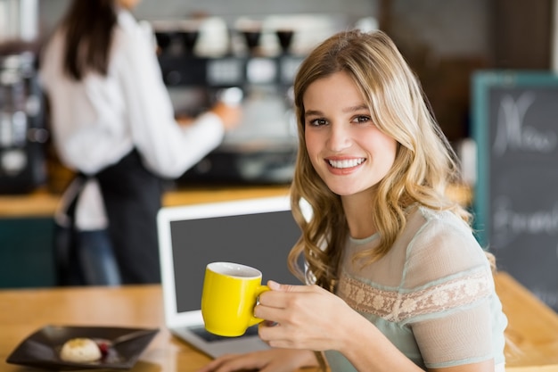 Portret van glimlachende vrouw die kop van koffie heeft