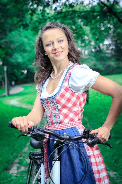 Foto portret van glimlachende vrouw met fiets in het park