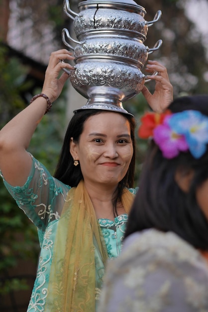 Foto portret van glimlachende vrouw met gezichtsverf die tijdens het evenement stapelcontainers op haar hoofd draagt
