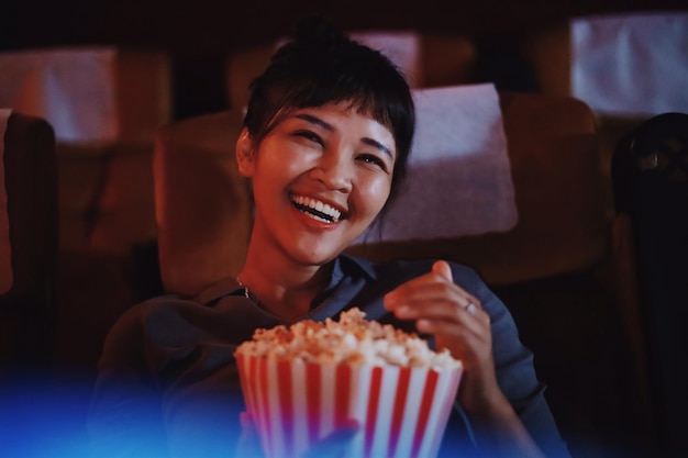 Portret van glimlachende vrouw met popcorn in het theater