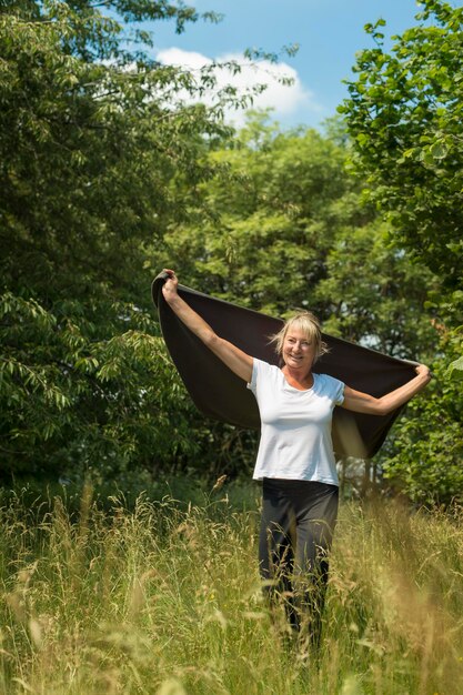 Foto portret van glimlachende vrouw met sjaal terwijl ze tegen bomen staat