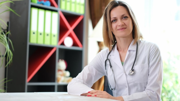 Portret van glimlachende vrouwelijke arts met stethoscoop in kliniek gelukkige jonge vrouwelijke therapeut of