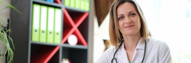 Portret van glimlachende vrouwelijke arts met stethoscoop in kliniek gelukkige jonge vrouwelijke therapeut of