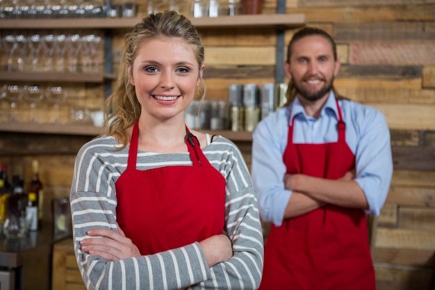 Portret van glimlachende vrouwelijke barista met mannelijke collega in coffeeshop