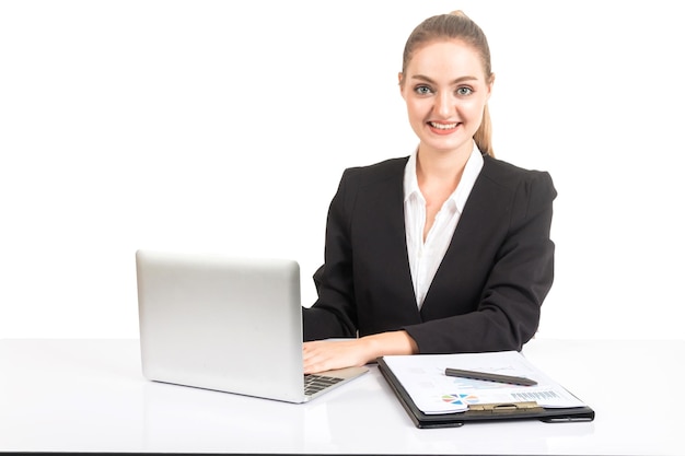 Portret van glimlachende zakenvrouw met een laptop terwijl ze aan het bureau zit tegen een witte achtergrond